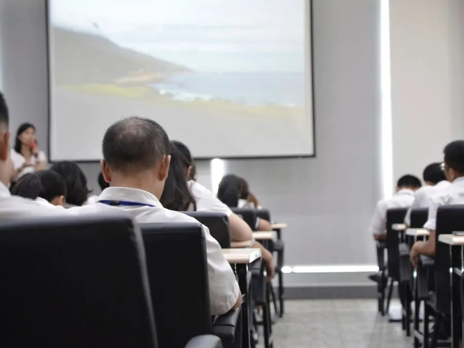 Attendees in a classroom training session facing a projector screen